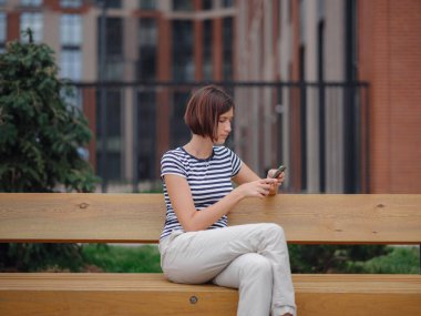 Sokakta cep telefonu kullanan gülümseyen kadın.