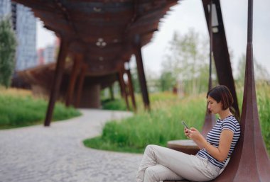 Güzel genç Asyalı kadın yaz günü çağdaş şehir parkında vakit geçiriyor..
