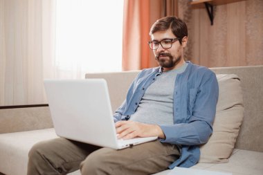 Evde dizüstü bilgisayar kullanan yakışıklı bir genç..