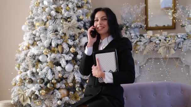 Feliz mujer de negocios en la habitación con el árbol de Navidad charlando en el teléfono celular — Vídeos de Stock