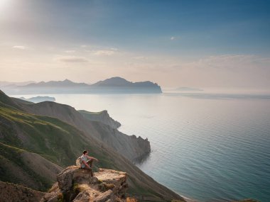 Genç adam dağların arka planında tek başına seyahat eder.