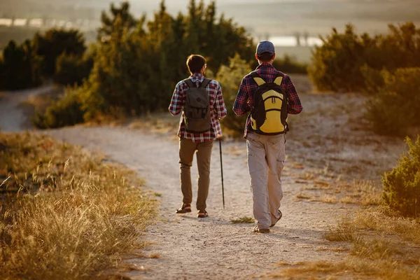 Deux hommes randonneurs profitent d'une promenade dans la nature, coucher de soleil en été — Photo