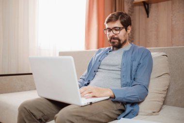 Evde dizüstü bilgisayar kullanan yakışıklı bir genç..