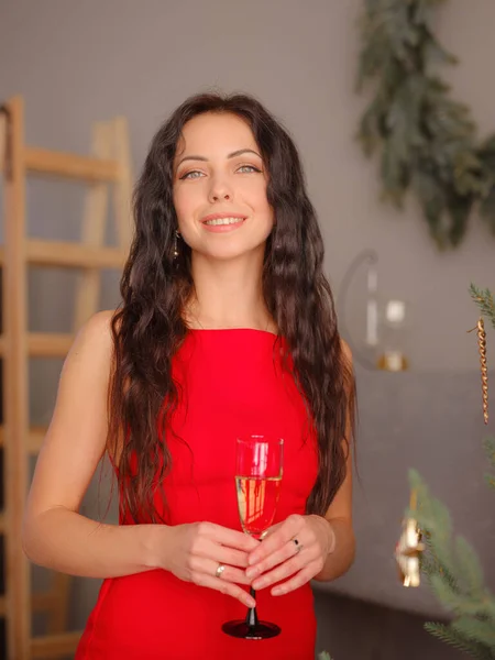 Lächelnde Frau im Abendkleid mit einem Glas Sekt über Weihnachtsbaumbeleuchtung Hintergrund — Stockfoto