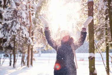 Mutlu Asyalı kadın kar ormanlarında yürüyor.