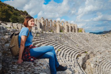 Sıcak Ekim öğleden sonra Antalya 'da yürüyüş. Eski Perge şehrinin kalıntılarında sırt çantalı güzel bir turist kadın.