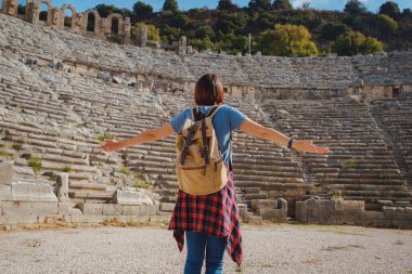 Sıcak Ekim öğleden sonra Antalya 'da yürüyüş. Eski Perge şehrinin kalıntılarında sırt çantalı güzel bir turist kadın.