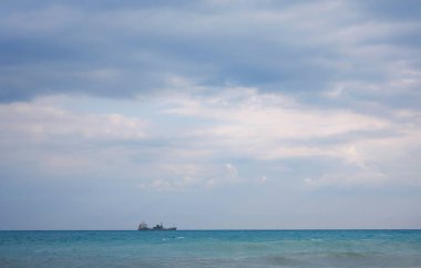 Kargo gemisi sakin mavi Akdeniz 'de, Anatalya' da. Akdeniz boyunca seyahat etmek, Antalya 'nın kayalık kıyılarını görmek. Uzakta, kargo gemileri görünüyor..