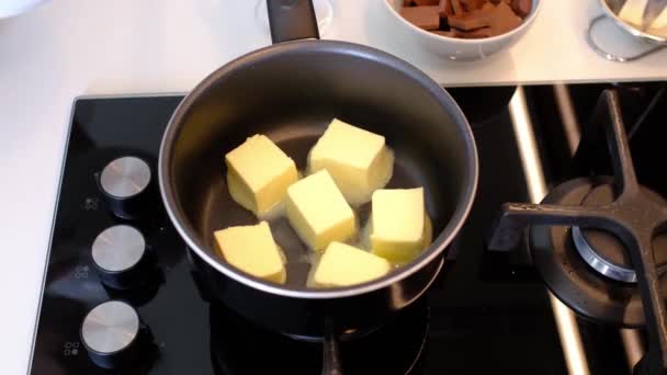 Schmelzen und Mischen eines Stücks Butter in einem Topf auf dem Gasherd, Butter wird flüssig. — Stockvideo