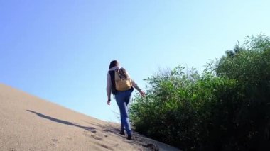 Patara kumullarında yürüyen sırt çantalı kadın.