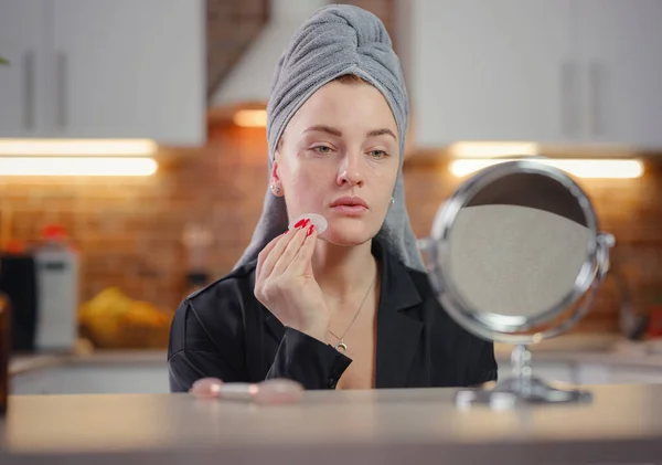 Young woman looks in mirror using facial gua sha jade board at home. — Stock Photo, Image