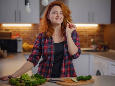 Mutfakta taze vejetaryen salatası pişiren ve yeni tarifler deneyen mutlu, sevimli bir kadın. Zayıflamak, Zayıflamak, Zayıflamak için Besin Tarifi