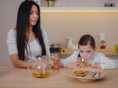 Evde mutfakta kurabiyelerle çay içen bir aile. Anne ve kızı evde birlikte mutlu bir an geçiriyorlar..