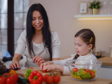 Mutlu anne ve kız mutfaktaki taze salatanın tadını çıkarın. diyet ve Sağlık kavramı.