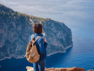 Butterfly Valley (kelebekler vadisi) in city of Oludeniz Fethiye in western Turkey. You can only reach this valley by boat or rock climbing. woman looks down on sea from cliff.