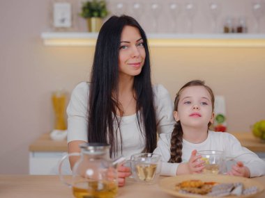 Evde mutfakta kurabiyelerle çay içen bir aile. Anne ve kızı evde birlikte mutlu bir an geçiriyorlar..