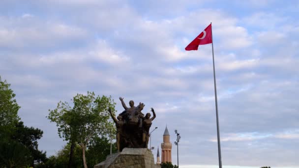 トルコのアナタリヤ 2021年12月19日 トルコ国旗が青空になびく アンタルヤ共和国広場 多数のカフェに囲まれた元大統領アタテュルクの騎馬像がある活気のある町の広場 — ストック動画