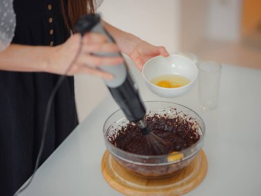 Kadın kakao tozu, şeker ve unu eritilmiş çikolatayla hamur yapmak ve lezzetli ev yapımı browni keki için ceviz yapmak üzere karıştırıyor. Ev hanımı konseptiyle yapılmış kek..