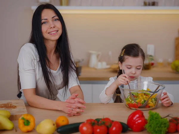Mutlu anne ve kız mutfaktaki taze salatanın tadını çıkarın. Evde sağlıklı yiyecekler. Sağlıklı Yaşam ve Yeme Konsepti. Sağlıklı beslenmeyle ilgili blog yazarken küçük bir etken