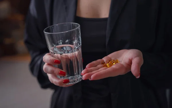 Kvinna i svart skjorta hålla i händerna piller omega 3 — Stockfoto
