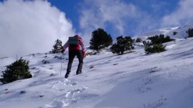 Dağcı güneşli kış gününde karlı dağın zirvesine ulaşır.