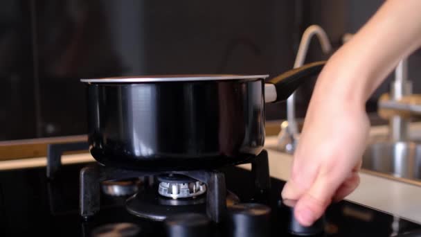 Frau stellt Topf auf Gasherd, schaltet Gas ein, um Mittag- oder Abendessen für die ganze Familie zu kochen — Stockvideo
