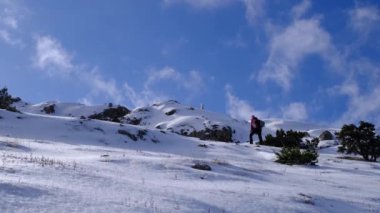 Dağcı güneşli kış gününde karlı dağın zirvesine ulaşır.