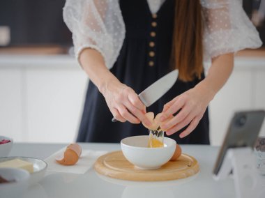 Evdeki mutfakta yemek pişirirken gülümseyen güzel bir genç kadın.