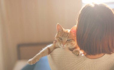 Kadın kedisiyle evdeki kanepede dinleniyor.