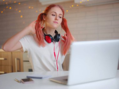 Mutfakta dizüstü bilgisayarla çalışan çekici genç bir kadın.