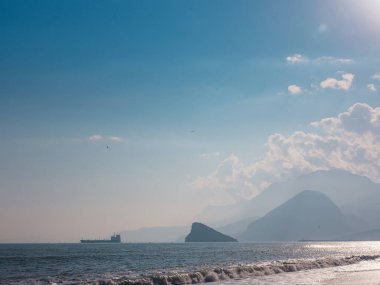 Kargo gemisi sakin mavi Akdeniz 'de, Anatalya' da. Akdeniz boyunca seyahat etmek, Antalya 'nın kayalık kıyılarını görmek. Uzakta, kargo gemileri görünüyor..