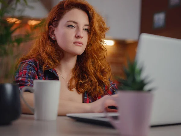 Beautiful young woman in casual clothes using laptop and smiling while working indoors, sitting next to hot coffee. technology woman concept for alternative freelance office