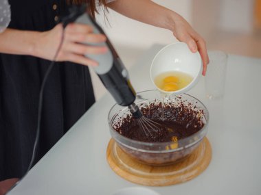 Kadın kakao tozu, şeker ve unu eritilmiş çikolatayla hamur yapmak ve lezzetli ev yapımı browni keki için ceviz yapmak üzere karıştırıyor. Ev hanımı konseptiyle yapılmış kek..