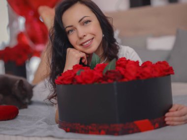 Beyaz elbiseli genç bir kadın yatakta oturuyor. Sabah aşkı yatak odası. Yıldönümü, mutlu yıllar, düğün, aşk günü, kadınlar günü, sevgililer günü ve olumlu duygular.