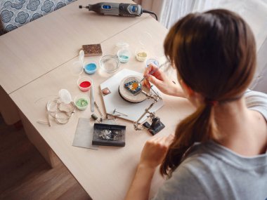 Hayat tarzı konsepti, evden çalışmak hayatını yeniden keşfetmek - mücevher tasarımcısı işyeri. Kadın mücevher yapar. Gürcistan minankari emaye üretim tekniği. Kuyumcu atölyede aksesuar yapıyor..