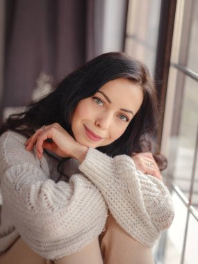 Beautiful young woman near window at home. Free Time To Relax. Happy lady taking break near window