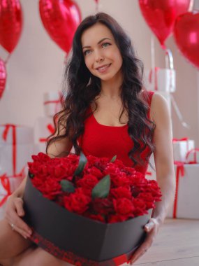 Kırmızı elbiseli güzel, mutlu genç bir kadın. Tatil partisi. Kırmızı kalp şeklinde balonlarla poz veren neşeli manken, eğlenen, Sevgililer Günü 'nü kutlayan. Aşkın sembolü