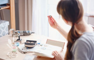 Hayat tarzı konsepti, evden çalışmak hayatını yeniden keşfetmek - mücevher tasarımcısı işyeri. Kadın mücevher yapar. Gürcistan minankari emaye üretim tekniği. Kuyumcu atölyede aksesuar yapıyor..