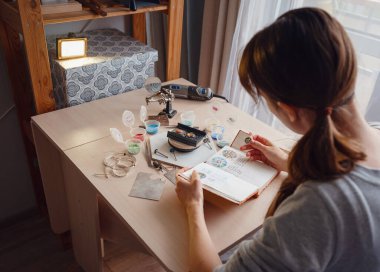 Hayat tarzı konsepti, evden çalışmak hayatını yeniden keşfetmek - mücevher tasarımcısı işyeri. Kadın mücevher yapar. Gürcistan minankari emaye üretim tekniği. Kuyumcu atölyede aksesuar yapıyor..