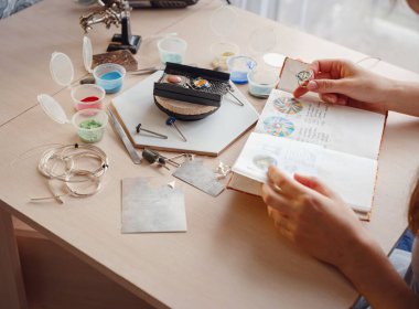 Hayat tarzı konsepti, evden çalışmak hayatını yeniden keşfetmek - mücevher tasarımcısı işyeri. Kadın mücevher yapar. Gürcistan minankari emaye üretim tekniği. Kuyumcu atölyede aksesuar yapıyor..