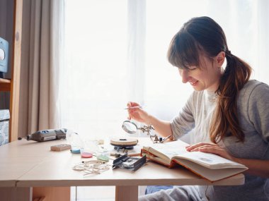 Hayat tarzı konsepti, evden çalışmak hayatını yeniden keşfetmek - mücevher tasarımcısı işyeri. Kadın mücevher yapar. Gürcistan minankari emaye üretim tekniği. Kuyumcu atölyede aksesuar yapıyor..