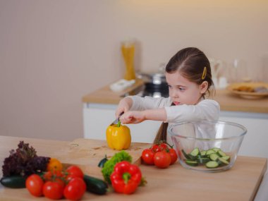 Genç Vlogger kız evde yemek pişirme hakkında sosyal medya videosu yapıyor, tripodla akıllı telefona bakıyor. Sağlıklı beslenmeyle ilgili bölüm. Çocukları erken yaşta sağlıklı beslenmeye çekme kavramı