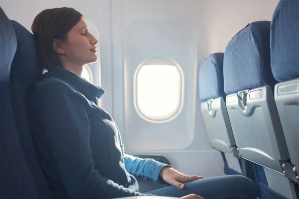 Fear of flying woman in plane sick with stress headache and motion sickness or airsickness. travel with airplane with aerophobia is afraid to fly, sitting on seat of plane.