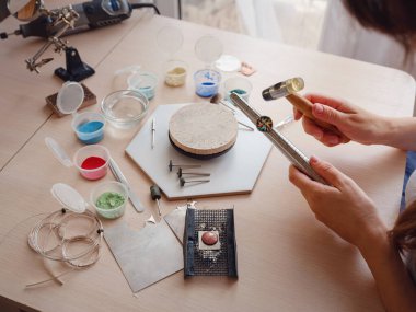 Hayat tarzı konsepti, evden çalışmak hayatını yeniden keşfetmek - mücevher tasarımcısı işyeri. Kadın yüzük ölçüsünü arttırmak için çalışıyor. Kuyumcu atölyede aksesuar yapıyor..