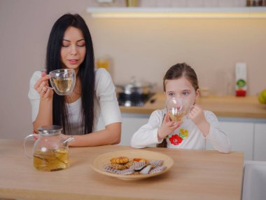 Evde mutfakta kurabiyelerle çay içen bir aile. Anne ve kızı evde birlikte mutlu bir an geçiriyorlar..