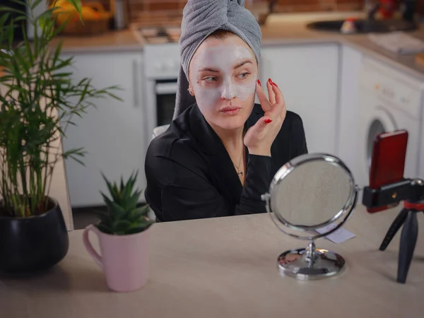Famous blogger. Cheerful female vlogger showing beauty mask while recording video and giving tips for her beauty blog. Woman testing new product. cosmetic face mask