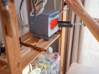 Hayat tarzı konsepti, evden çalışmak hayatını yeniden keşfetmek - mücevher tasarımcısı işyeri. Kadın mücevher yapar. Gürcistan minankari emaye üretim tekniği. Kuyumcular için eritme fırınıyla çalışmak