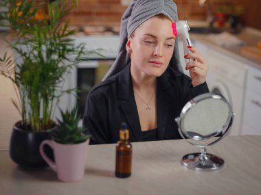 Genç kadın Ultrasonik Cilt Temizleyici Asa kullanıyor. Cilt bakımı ve yaş kozmetik konsepti. Yıkama ve masaj yüz, spa prosedürleri, kadın yüz bakımı, kirin gözeneklerini temizleme.