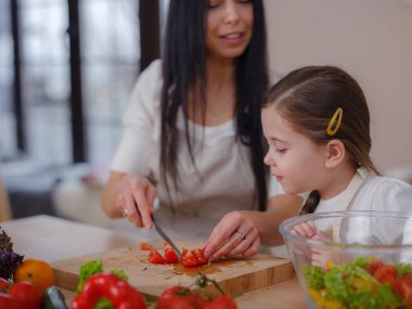 Mutlu anne ve kız mutfaktaki taze salatanın tadını çıkarın. Evde sağlıklı yiyecekler. Sağlıklı Yaşam ve Yeme Konsepti. Sağlıklı beslenmeyle ilgili blog yazarken küçük bir etken