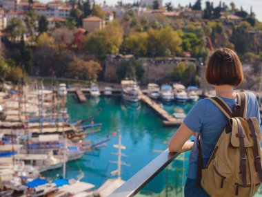 Türkiye 'ye, eski Antalya Kaleci' ye. Eski şehirde sırt çantalı mutlu Asyalı turist kadın yürüyüşçüler. Eski kasabayı ve limanı gözetleyen bir kadın var.